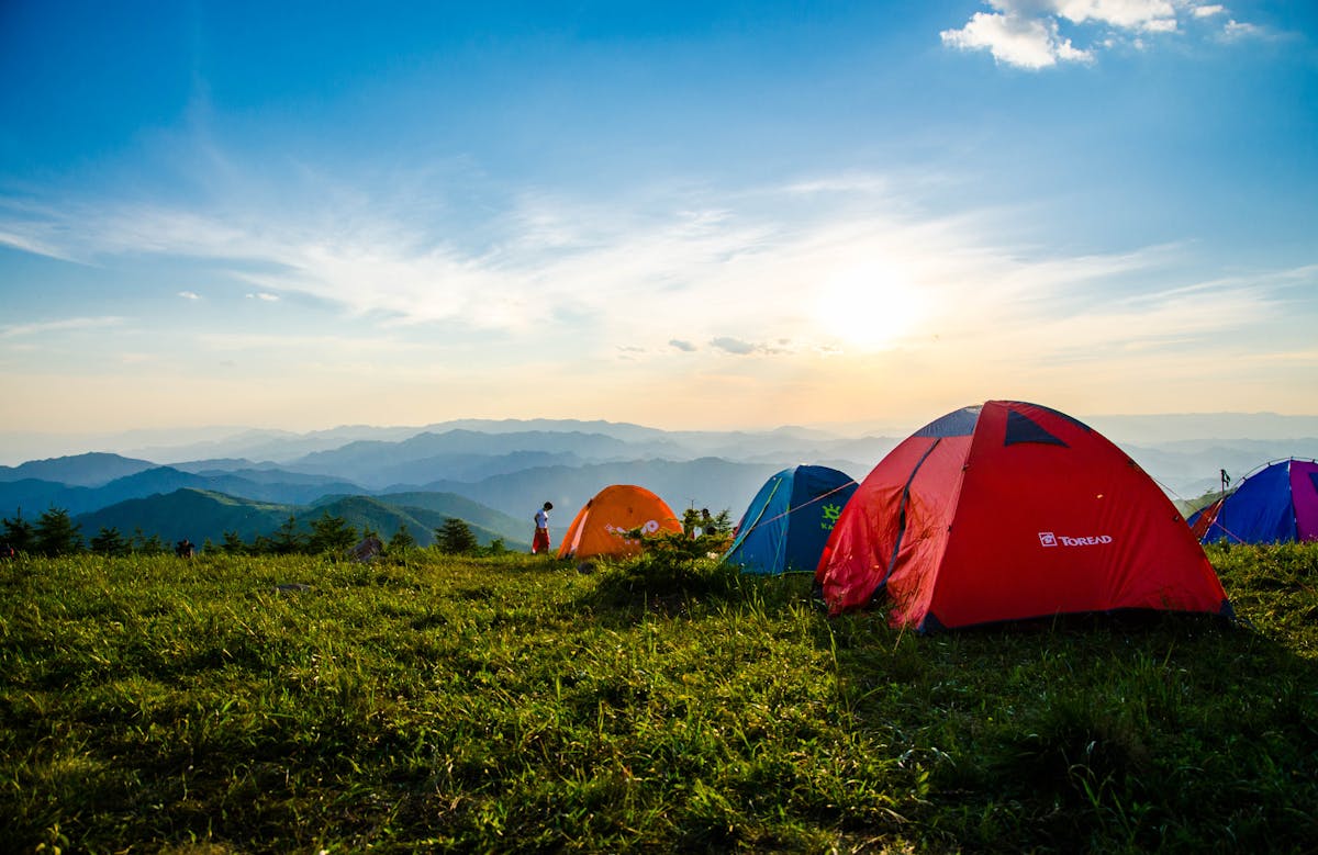 Backpacker setting up sleeping pad beside a mountain lake at golden hour