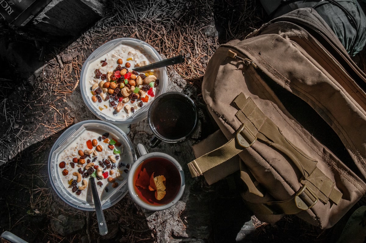 Organized backpacking food bags sorted by day with labeled ziplock bags on a rock at a campsite