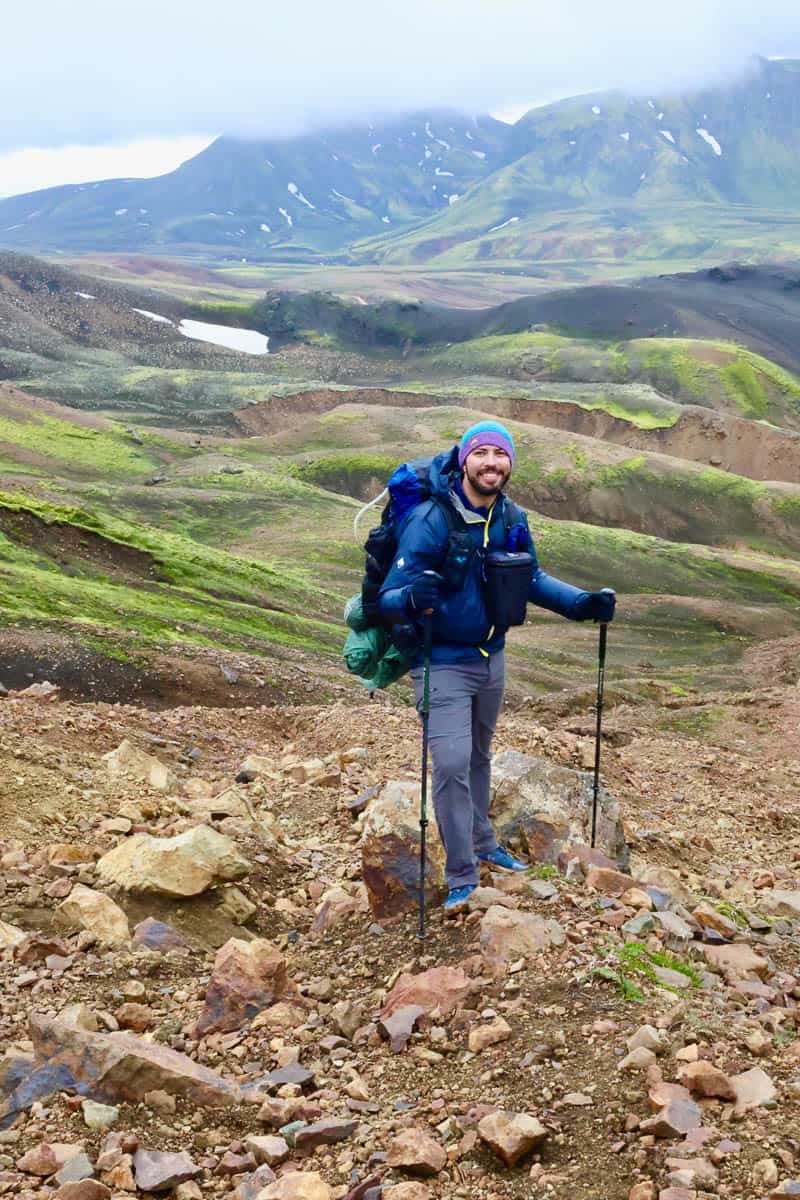 Backpacker resting at a mountain overlook removing hiking boots to check feet