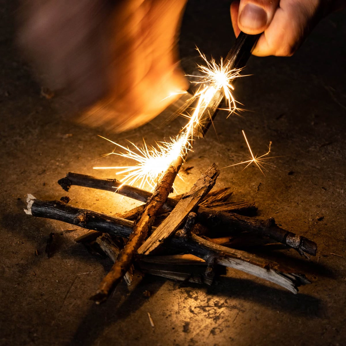 Hands holding a ferro rod striker with sparks flying