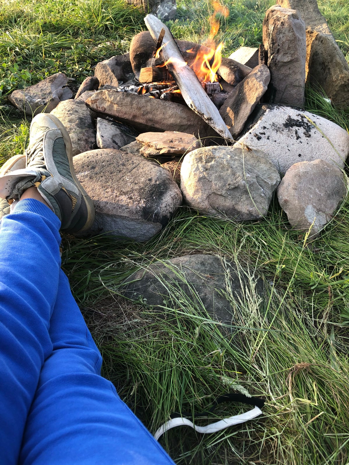 Campfire in established fire ring at dusk, well-contained