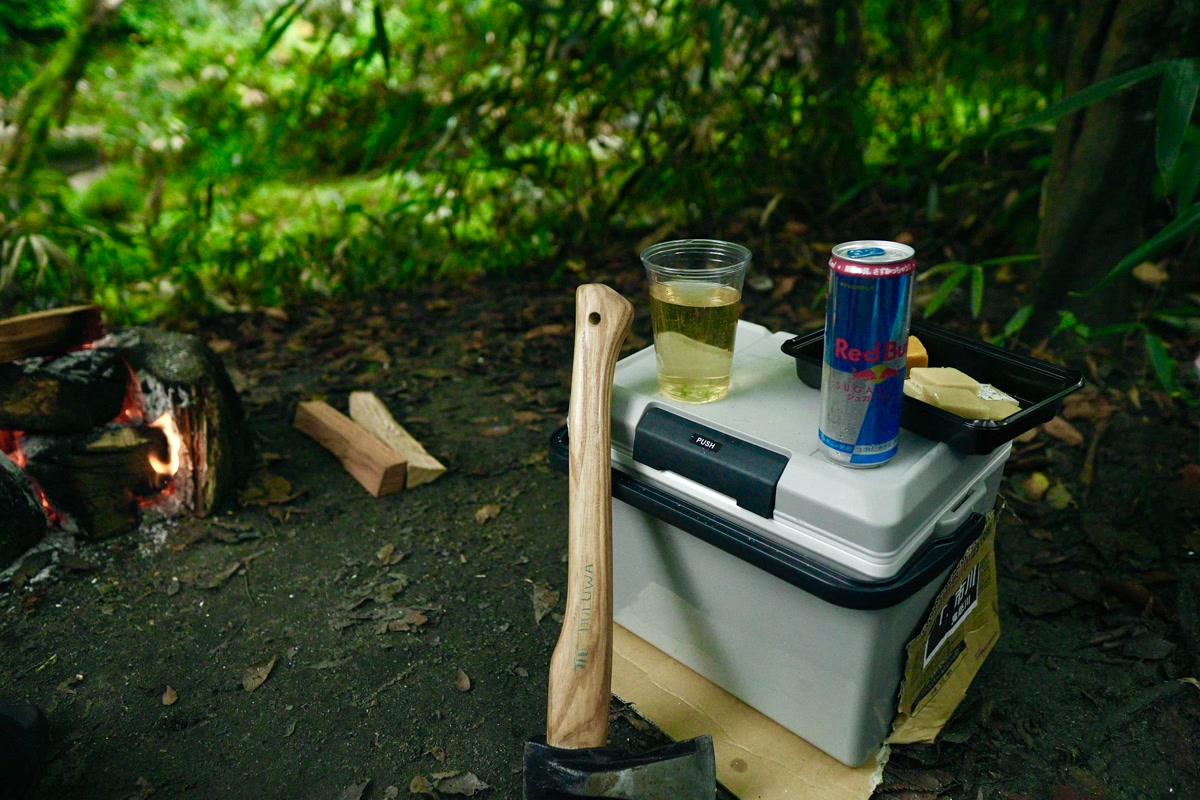 Rotomolded camping cooler sitting open at a forest campsite with ice and food inside