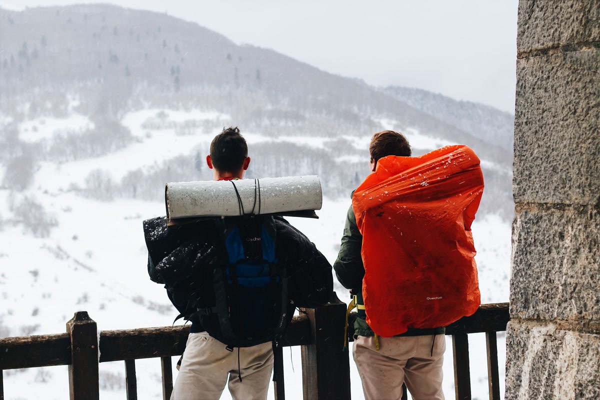 Hiker adjusting backpack straps on mountain trail