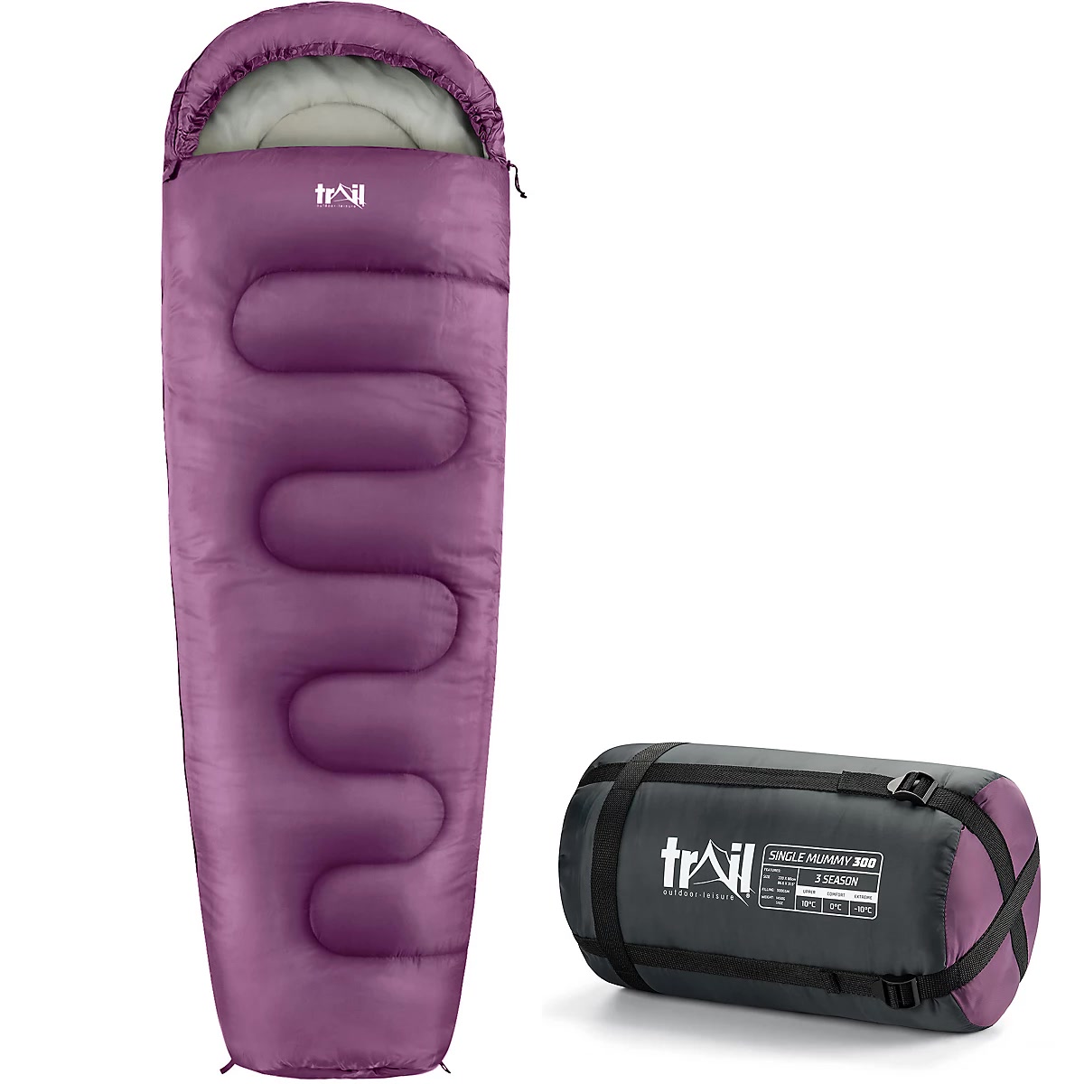 Down sleeping bag compressed in a stuff sack next to a backpack at a forest campsite