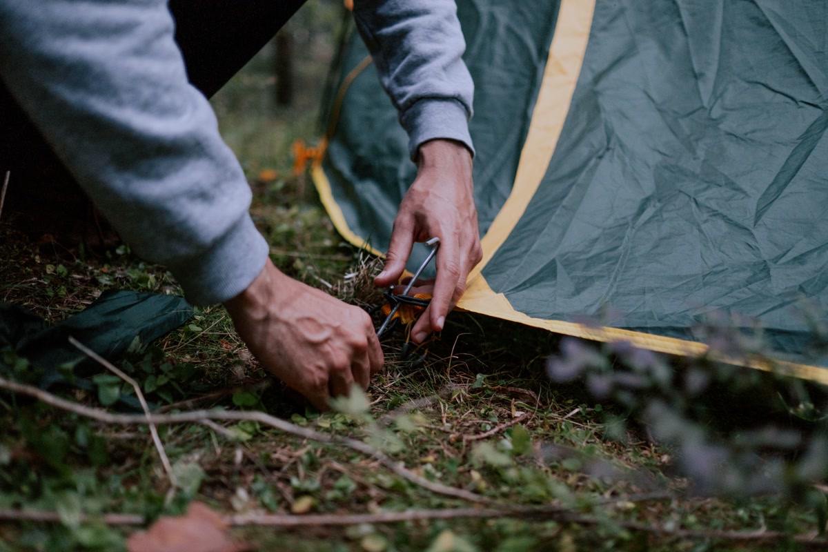 Hand pulling titanium shepherd hook tent stake from rocky mountain soil