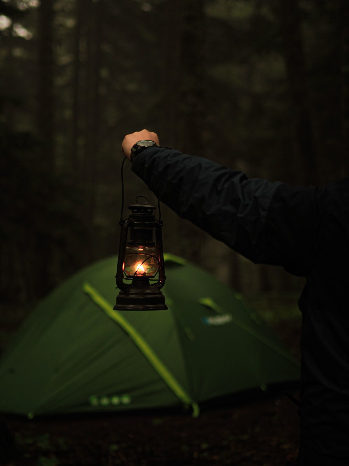 Glowing LED camping lantern hanging inside a dome tent at night