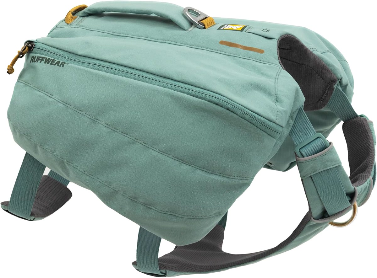Close-up of a dog hiking backpack with saddlebags loaded with water bottles and bowls on a rock at a trail rest stop